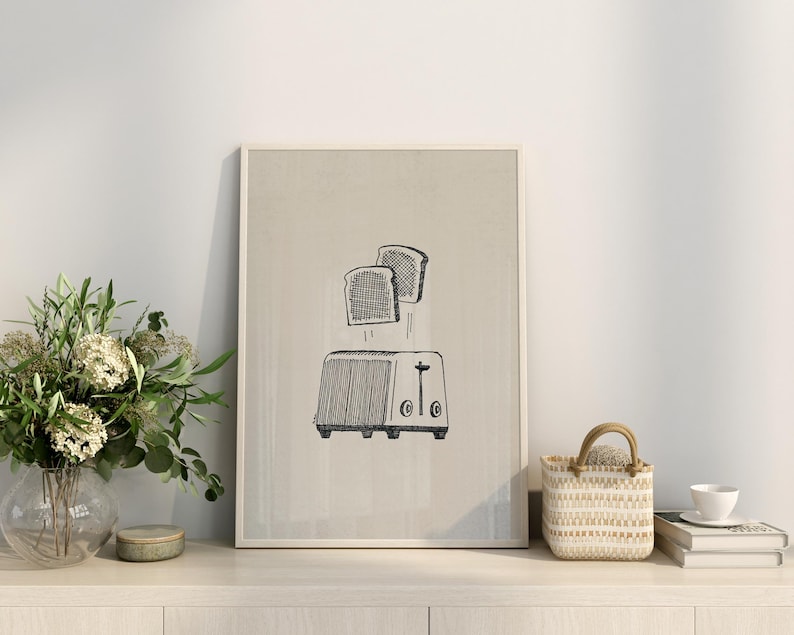 Puede incluir: Una ilustraci&oacute;n en blanco y negro de dos rebanadas de pan que salen de una tostadora. La ilustraci&oacute;n est&aacute; sobre un fondo beige y enmarcada en un marco blanco.