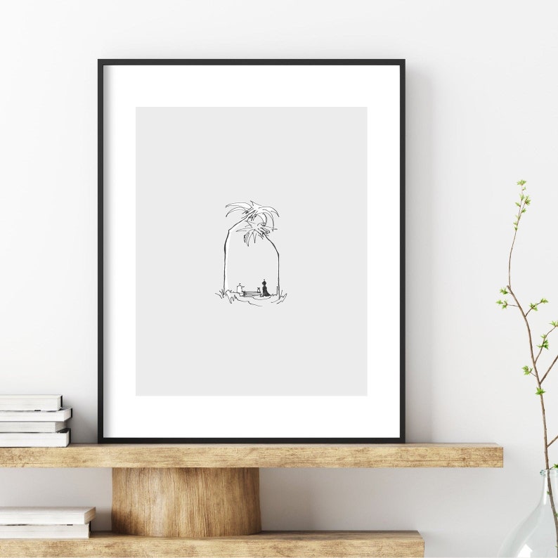 May include: Black and white line drawing of a person sitting under a palm tree. The drawing is framed and displayed on a shelf.