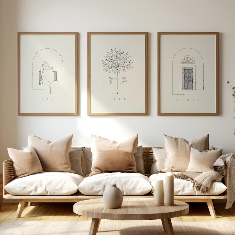 Puede incluir: Tres impresiones art&iacute;sticas enmarcadas con dibujos lineales minimalistas y texto. Las impresiones presentan un par de manos en oraci&oacute;n, un &aacute;rbol y una puerta. Los marcos son de color marr&oacute;n claro y las impresiones se exhiben sobre un sof&aacute;.