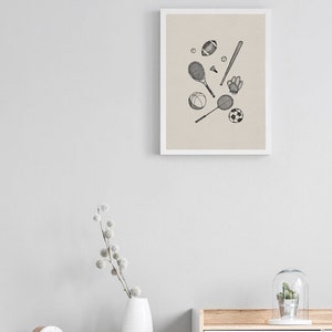 K&ouml;nnte beinhalten: Ein gerahmter Kunstdruck mit handgezeichneten Sportger&auml;ten. Die Illustration zeigt einen Football, Baseballschl&auml;ger, Tennisschl&auml;ger, einen Fu&szlig;ball und einen Baseballhandschuh, alle in Schwarz-Wei&szlig;.