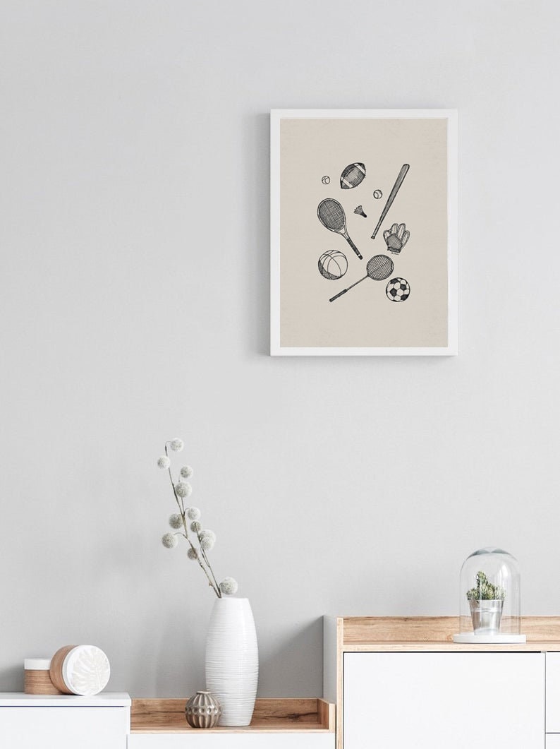 K&ouml;nnte beinhalten: Ein gerahmter Kunstdruck mit handgezeichneten Sportger&auml;ten. Die Illustration zeigt einen Football, Baseballschl&auml;ger, Tennisschl&auml;ger, einen Fu&szlig;ball und einen Baseballhandschuh, alle in Schwarz-Wei&szlig;.