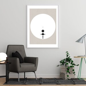 May include: A framed print with a minimalist design featuring a white circle with black dots and lines on a beige background.