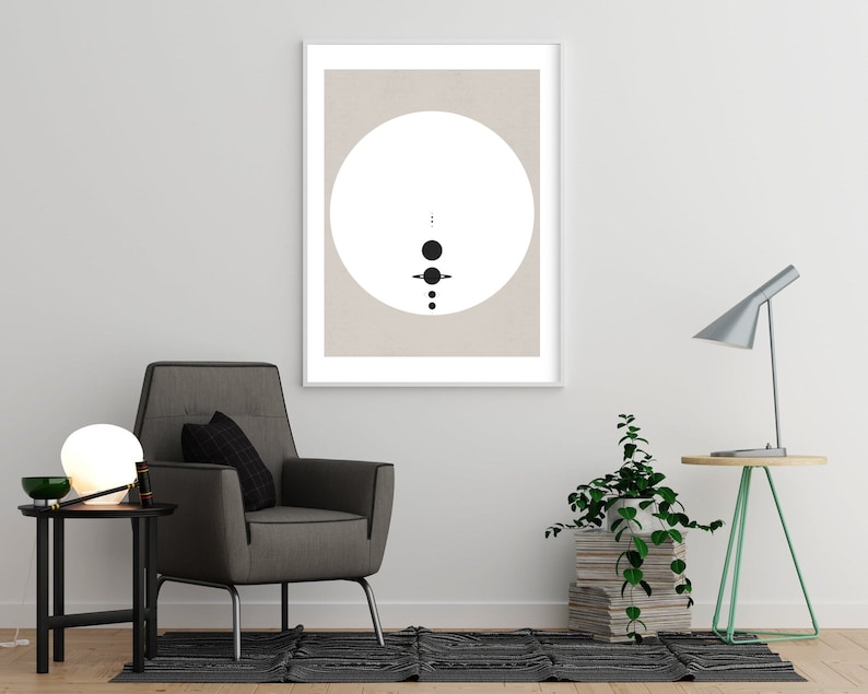 May include: A framed print with a minimalist design featuring a white circle with black dots and lines on a beige background.