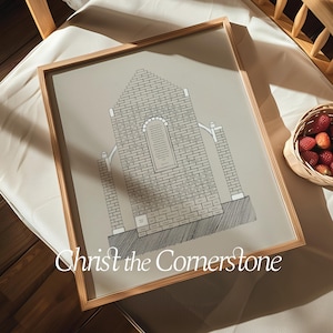 Pode incluir: Uma impressão emoldurada de um edifício da igreja com uma fachada de tijolo e o texto "Christ the Cornerstone" na parte inferior. A impressão está em uma moldura marrom clara e está sobre uma superfície branca.