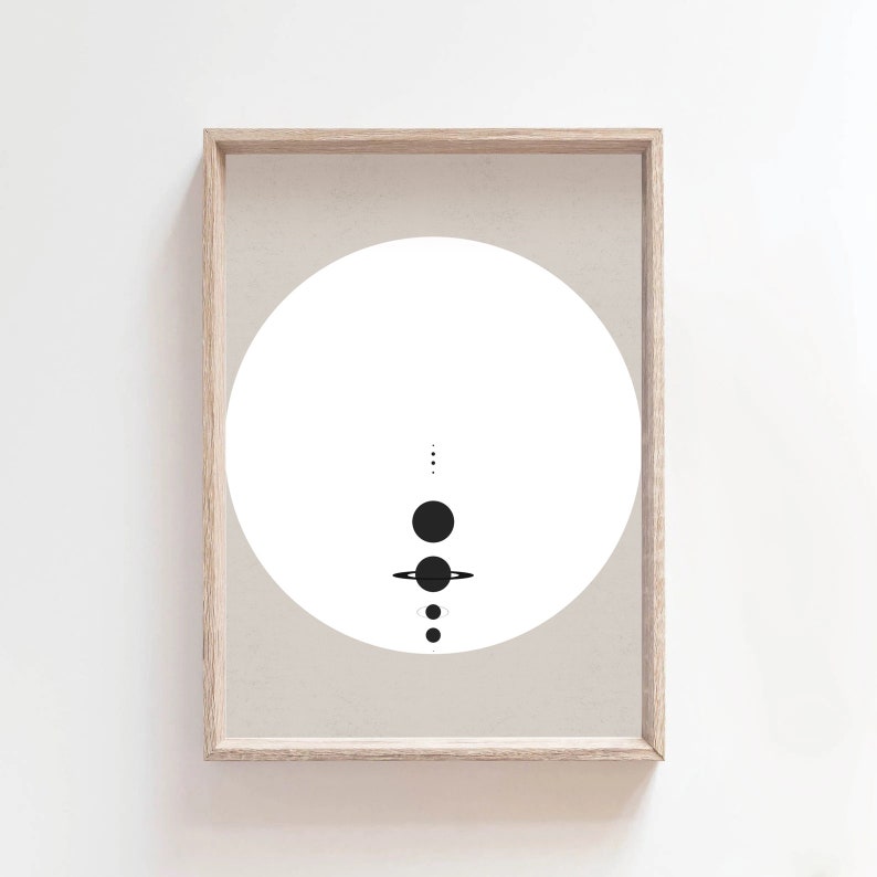 May include: A minimalist black and white print of a solar system with planets and rings in a circle on a beige background. The print is framed in a light wood frame.
