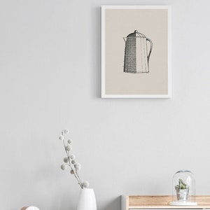 May include: A black and white line drawing of a coffee pot in a white frame on a light gray wall. The frame is hanging above a white dresser with a wooden top. A white vase with a dried flower arrangement is on the dresser.