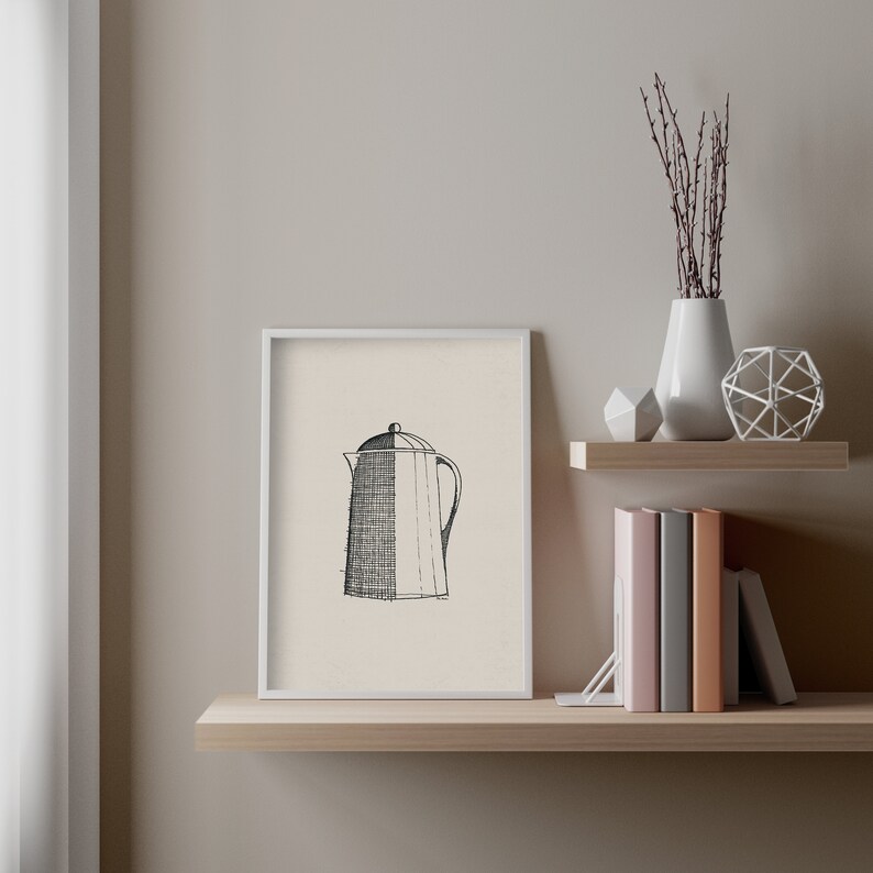 May include: A black and white line drawing of a coffee pot in a white frame on a wooden shelf with a vase of dried branches and a geometric metal sculpture.