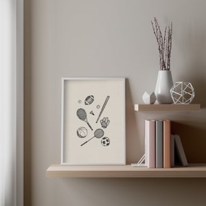 K&ouml;nnte beinhalten: Ein gerahmter Kunstdruck mit schwarz-wei&szlig;en Illustrationen von Sportger&auml;ten. Dargestellt sind ein Baseballschl&auml;ger, Tennisschl&auml;ger, ein Football, ein Basketball, ein Fu&szlig;ball und ein Baseballhandschuh. Der Druck befindet sich auf einem Holzregal.