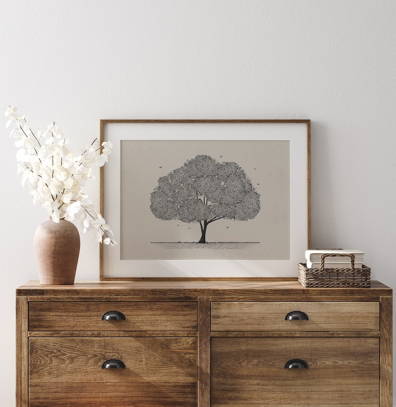 May include: A framed black and white line drawing of a tree with a simple background. The frame is brown wood and the drawing is on a beige background. The drawing is on a wooden dresser with two drawers.