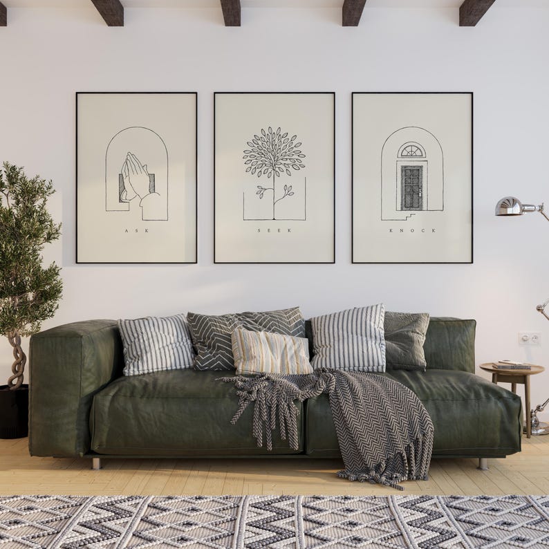 Puede incluir: Tres impresiones art&iacute;sticas enmarcadas con dibujos lineales minimalistas. Las impresiones presentan las palabras "ASK", "SEEK" y "KNOCK" debajo de im&aacute;genes de manos, un &aacute;rbol y una puerta. Un sof&aacute; verde con cojines y una manta se encuentra debajo.