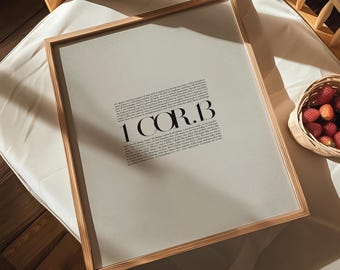 May include: A framed print with a beige background and black text. The text reads "1 COR. 13" and includes a passage of scripture. The frame is light brown wood.