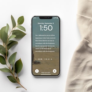 Pu&ograve; includere: Lo schermo di uno smartphone che mostra un versetto biblico di 1 Corinzi 15:3-4. Il versetto parla della morte, della sepoltura e della risurrezione di Ges&ugrave; Cristo. L'immagine di sfondo &egrave; un paesaggio desertico. L'ora sul telefono &egrave; le 1:50.