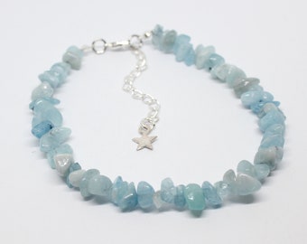 May include: A delicate aquamarine chip bracelet with a silver star charm. The bracelet is made with small, irregular shaped stones and has a silver clasp.