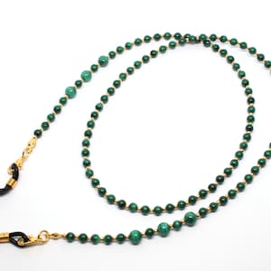 May include: A green malachite and gold chain eyeglass holder. The chain is made of small gold beads with green malachite beads interspersed throughout.