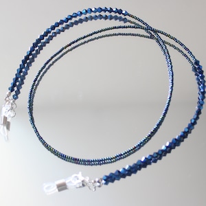 May include: A pair of blue crystal beaded eyeglass chains with silver metal clasps. The chains are made of two strands of beads, one strand is larger than the other.