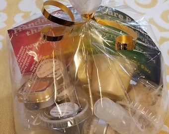Könnte beinhalten: Eine durchsichtige Plastiktüte gefüllt mit verschiedenen kleinen Behältern mit Schönheitsprodukten. Die Tüte ist mit einem goldenen Band gebunden und hat eine kleine Karte mit dem Text "Handmade" darauf.