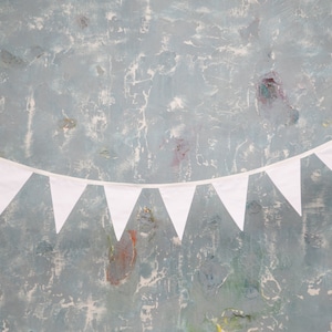 May include: A white bunting banner with triangular flags hangs against a textured blue background.