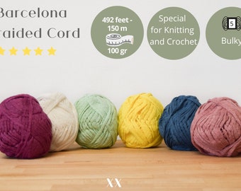 May include: Six balls of braided cord yarn in various colors, including burgundy, cream, green, yellow, blue, and pink. The yarn is labeled "Barcelona Braided Cord" and is described as "Special for Knitting and Crochet" and "Bulky 5". The yarn is 492 feet (150 meters) and weighs 100 grams.