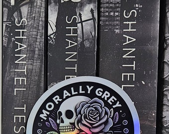 May include: A holographic sticker with a black and white illustration of a skull with a rose, books, and a heart. The text on the sticker reads "Morally Grey Book Club".
