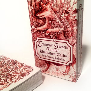 May include: A deck of Creatures' Animal Secrets Divination Cards by Yelizaweta Bakhtina. The box features a red illustration of a fox in a forest setting.
