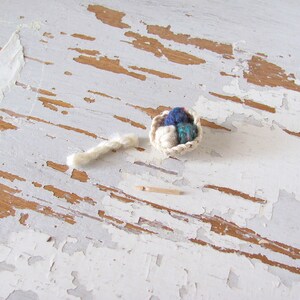 Inch to Foot Scale 1:12 Miniature Dollhouse Wood Crochet Hook Yarn Needle, Roombox Model Collector Textile Fiber Artist Handspinner Gift. Styled with a small white crocheted basket filled with balls of yarn and a skein of yarn.