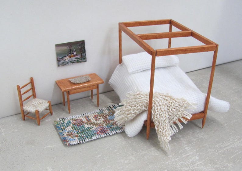 Little Handmade Half Inch to Foot Dollhouse Bed Throw Blanket, 1:24 Scale Miniature Artisan Hand Knit Ivory Cream White Bedspread, Doll House Furniture Bedroom Bedding, Collector Model Home Decor Accent Textile for Traditional Style or Modern Country Farmhouse, Cabin, or Cottage. Styled draped on the corner of a four post bed with white bedspread, with a brocade rug, chair, table with linen mat, and winter landscape painting on the wall.
