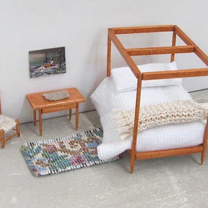 Little Handmade Half Inch to Foot Dollhouse Bed Throw Blanket, 1:24 Scale Miniature Artisan Hand Knit Ivory Cream White Bedspread, Doll House Furniture Bedroom Bedding, Collector Model Home Decor Accent Textile for Traditional Style or Modern Country Farmhouse, Cabin, or Cottage. Styled folded across the end of a four post bed with white bedspread, with a brocade rug, chair, table with linen mat, and winter landscape painting on the wall.