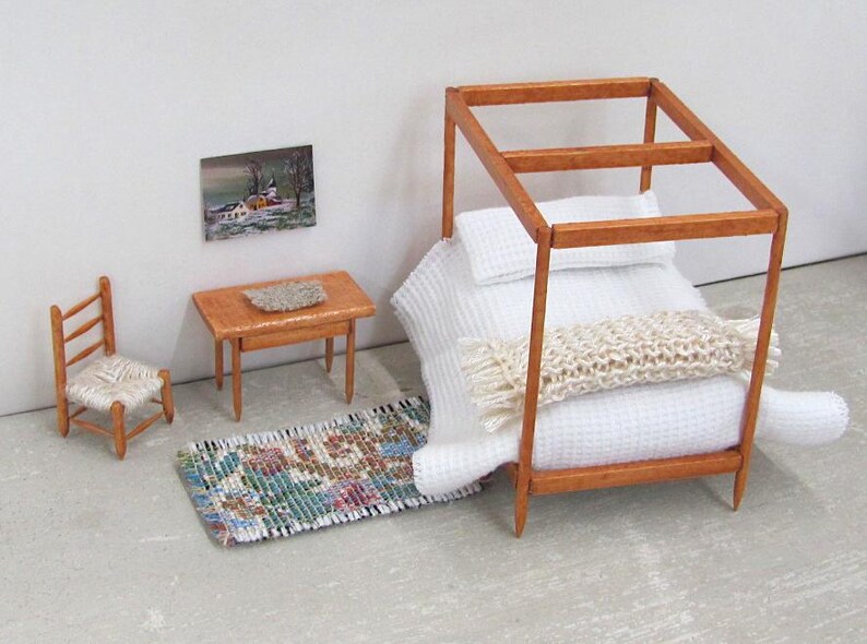 Little Handmade Half Inch to Foot Dollhouse Bed Throw Blanket, 1:24 Scale Miniature Artisan Hand Knit Ivory Cream White Bedspread, Doll House Furniture Bedroom Bedding, Collector Model Home Decor Accent Textile for Traditional Style or Modern Country Farmhouse, Cabin, or Cottage. Styled folded across the end of a four post bed with white bedspread, with a brocade rug, chair, table with linen mat, and winter landscape painting on the wall.