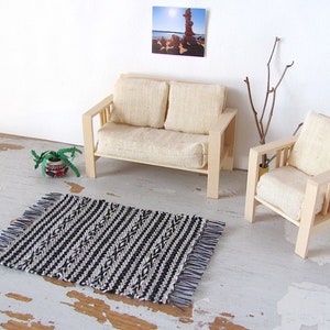 Handmade Inch to Foot Dollhouse Miniature Rug or Carpet,  1:12 Scale Artisan Hand Woven Black and Off-White Stripe and Diamond Pattern Scandinavian Modern, Rustic Farmhouse, Beach Cottage, or Southwest Desert Ranch Collector Dolls House Furniture Accessory Textile. Styled with a couch and chair, a floor vase with sticks, a potted cactus, and a rock photo on the wall.