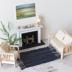 Handcrafted, Inch to Foot Dollhouse Miniature Rug is 1:12 Scale Artisan Hand Loom Woven in Indigo Navy Ocean Blue, Beige, and White Stripe Floor Carpet for Modern Coastal Seaside Nautical Beach House, Cabin Decor Doll House Furniture Accessory. Styled with a chair and couch in front of a fireplace, with a green plant in a floor vase and marsh landscape.