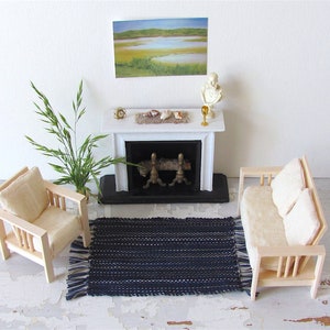 Handcrafted, Inch to Foot Dollhouse Miniature Rug is 1:12 Scale Artisan Hand Loom Woven in Indigo Navy Ocean Blue, Beige, and White Stripe Floor Carpet for Modern Coastal Seaside Nautical Beach House, Cabin Decor Doll House Furniture Accessory. Styled with a chair and couch in front of a fireplace, with a green plant in a floor vase and marsh landscape.