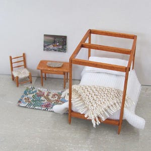 Little Handmade Half Inch to Foot Dollhouse Bed Throw Blanket, 1:24 Scale Miniature Artisan Hand Knit Ivory Cream White Bedspread, Doll House Furniture Bedroom Bedding, Collector Model Home Decor Accent Textile for Traditional Style or Modern Country Farmhouse, Cabin, or Cottage. Styled folded in a triangle on the end of a four post bed with white bedspread, with a brocade rug, chair, table with linen mat, and winter landscape painting on the wall.
