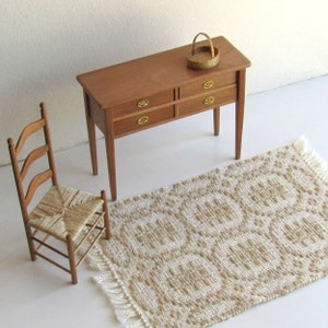 May include: A wooden dresser with four drawers and a woven rug with a geometric pattern. A wooden chair with a woven seat sits next to the dresser.