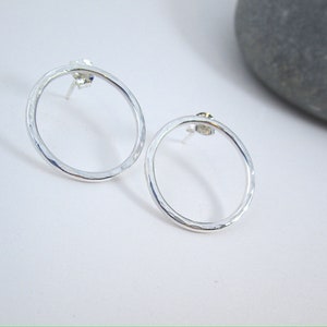 May include: A pair of silver circle stud earrings with a hammered texture.