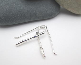 Può includere: Un paio di orecchini d'argento con un design semplice e minimalista. Gli orecchini sono realizzati con un filo sottile e curvo che forma un gancio.