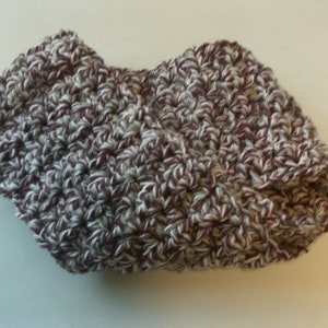 May include: A crocheted hat in a mix of white, grey, and burgundy yarn. The hat features a folded brim and a textured stitch pattern. The hat appears soft and warm, suitable for cooler weather.