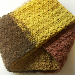 May include: A crocheted neck warmer in brown, yellow, and orange tones. The neck warmer is made of soft yarn and has a simple, classic design.