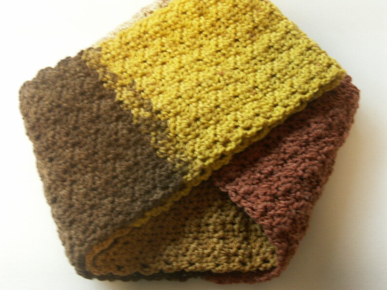 May include: A crocheted neck warmer in brown, yellow, and orange tones. The neck warmer is made of soft yarn and has a simple, classic design.