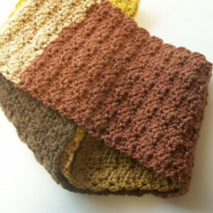 May include: A brown, beige, and yellow crocheted scarf with a textured pattern.