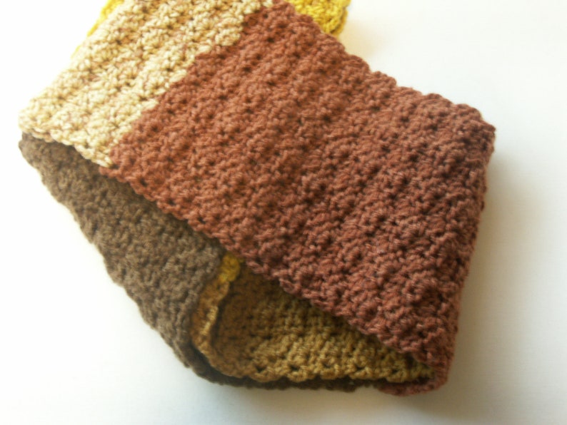 May include: A brown, beige, and yellow crocheted scarf with a textured pattern.