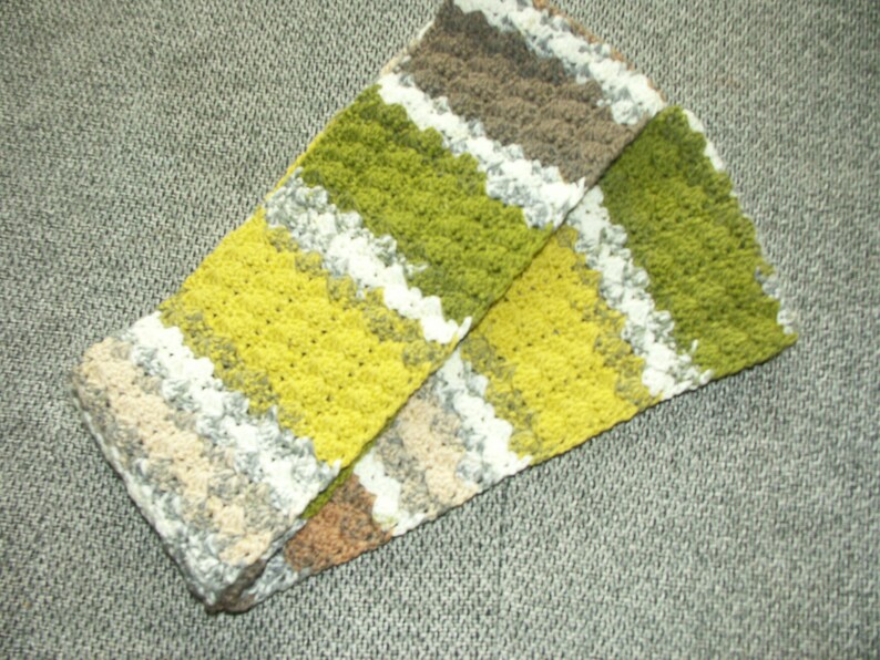 May include: A crocheted scarf with stripes of green, yellow, white and brown.