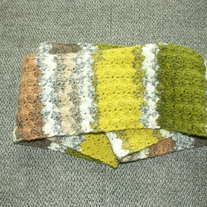 May include: A crocheted scarf with stripes of brown, white, beige, yellow, and green.