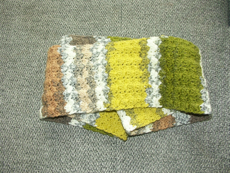 May include: A crocheted scarf with stripes of brown, white, beige, yellow, and green.