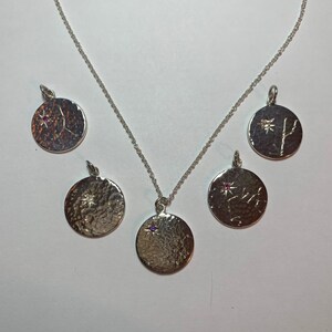 May include: Five silver necklaces with round pendants featuring different star constellations. Each pendant has a small gemstone in the center.