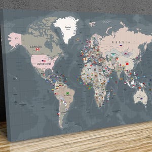 May include: A rectangular wall art print featuring a world map with a dark grey background and light grey landmasses. The map displays country names such as Canada, United States, Russia, and Brazil, along with small national flags placed on each country.
