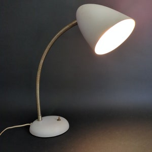 May include: A white desk lamp with a flexible gooseneck arm and a white shade. The lamp has a simple design and a classic look.