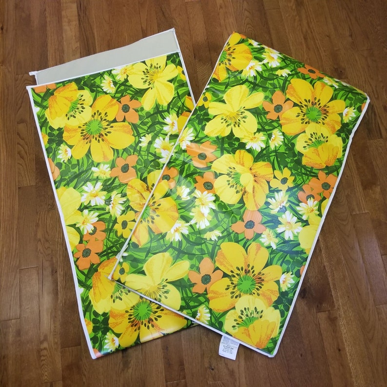 Pode incluir: Dois tapetes de mesa com padr&atilde;o floral amarelo e verde com bordas brancas. Os tapetes de mesa apresentam um padr&atilde;o repetitivo de flores amarelas com centros laranja sobre um fundo verde.