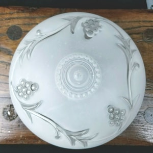 May include: White frosted glass ceiling light fixture with a grapevine design. The fixture has a circular center with a beaded edge.