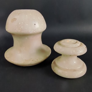 May include: Two white ceramic insulators, one tall and one short, with a smooth, slightly textured surface.