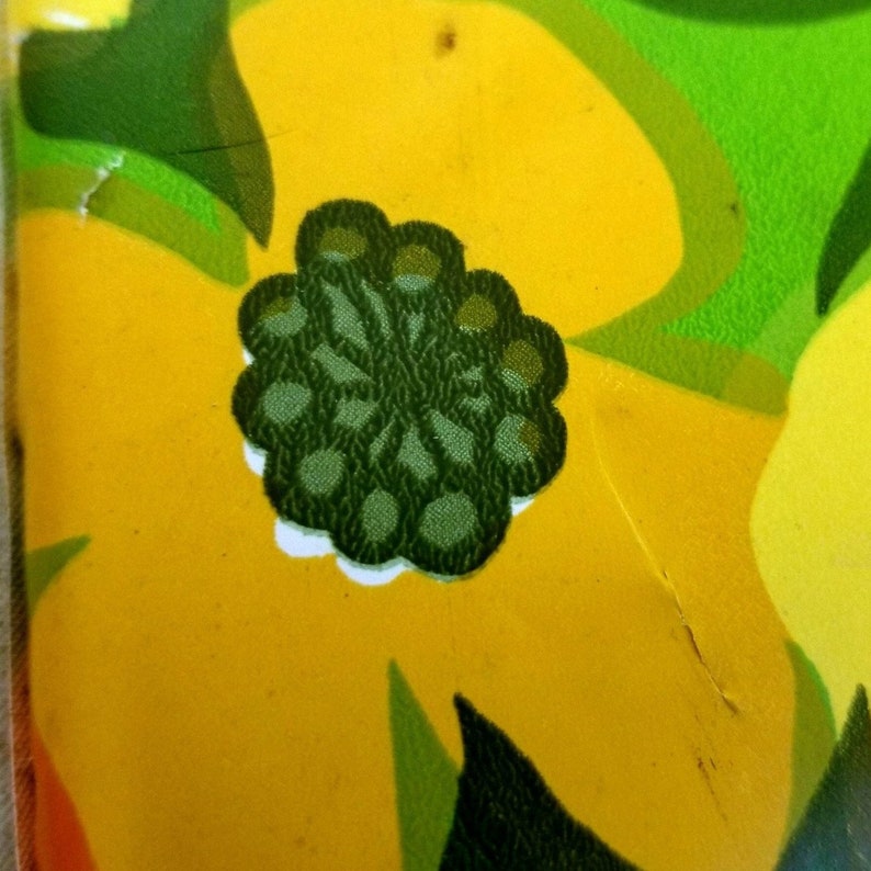 Pode incluir: Um close-up de um desenho floral verde em um fundo amarelo. O desenho &eacute; uma flor estilizada com um contorno branco.